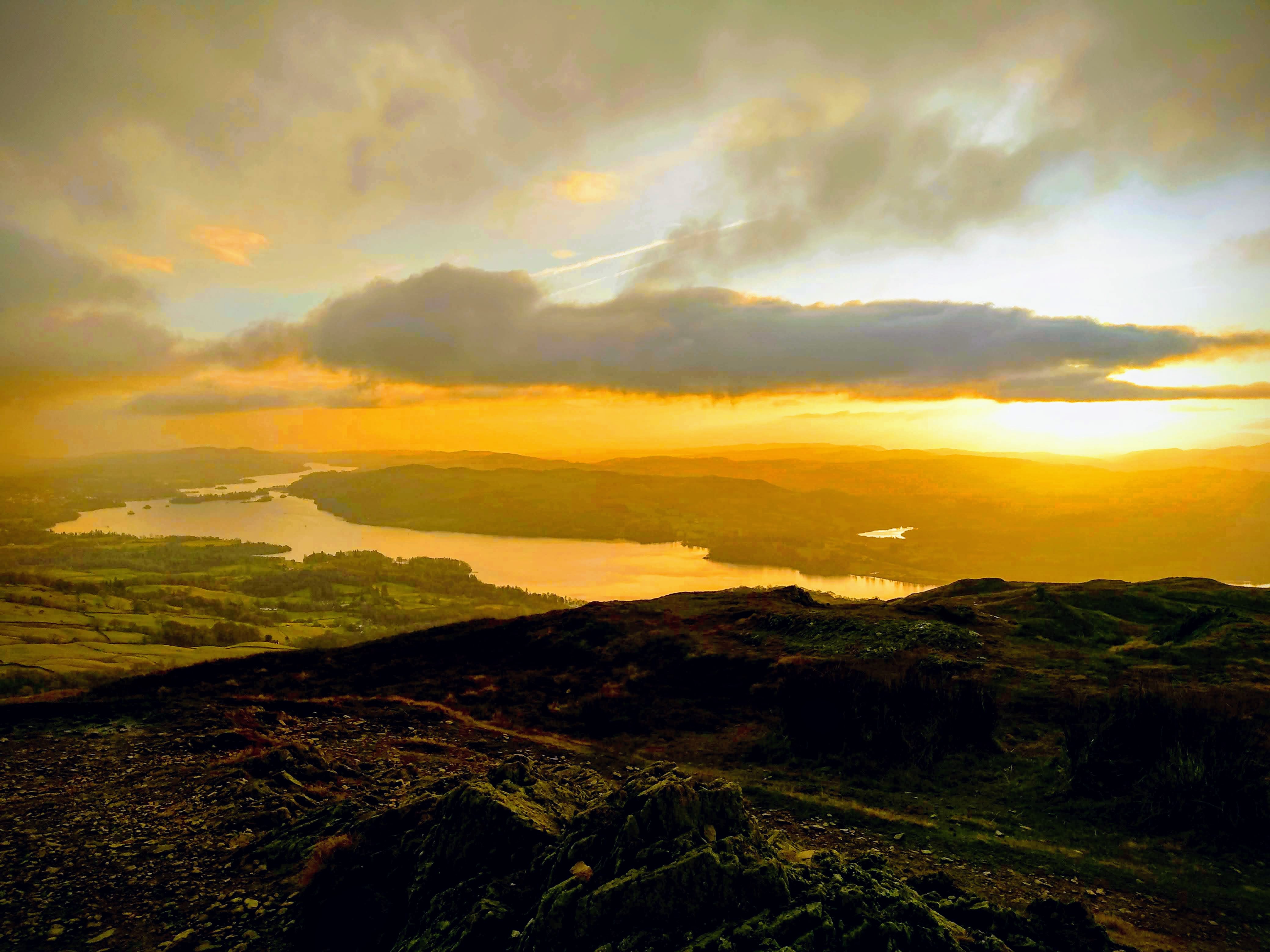 A landscape photograph over the sunset over a lake from the top of a hill.